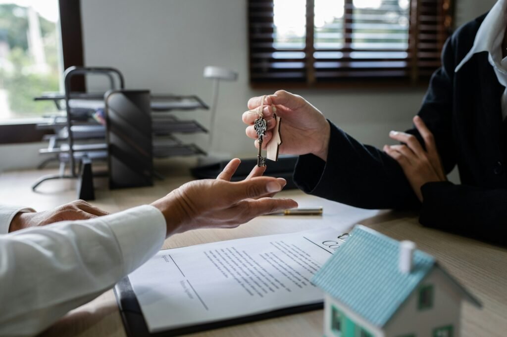 Happy real state agent giving new house key to a young couple. Real estate concept